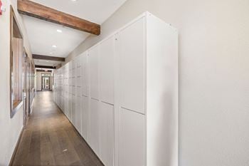 A long row of white cabinets in a hallway with wood floors
